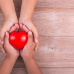 Two sets of hands holding a heart