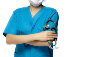 Nurse crossing arms holding stethoscope with a mask on.