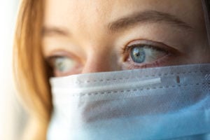 Woman nurse with a blue medical mask with depressed eyes.