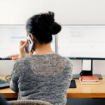 Nurse on phone looking at computer screens while working from home