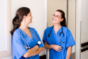 Two nurses having friendly discussion in hallway