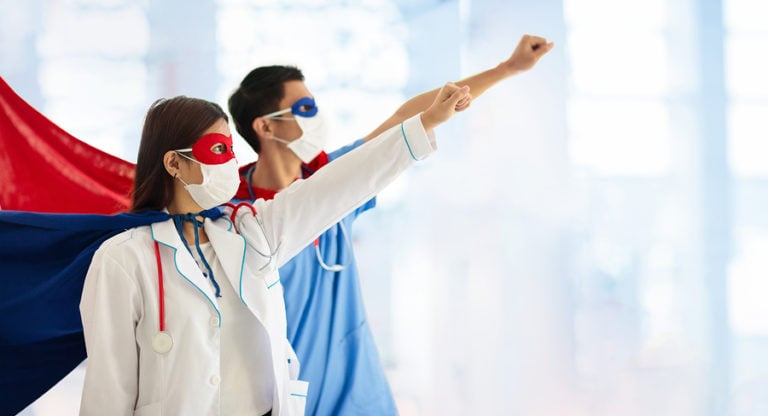 Male and female nurses wearing capes in Superman pose