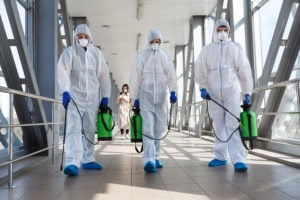 Sanitation crew in hazmat suits spraying down hallway