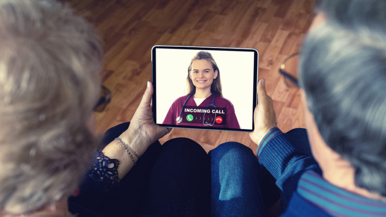 Senior couple sitting next to each other holding a tablet or IPad about to talk with nurse