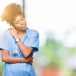 Young female African American nurse gives herself a hug