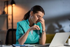 Tired female night shift nurse looking at computer