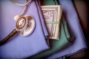 Stethoscope and nurse scrubs with cash - APRN salary