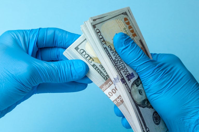 RN with gloves holding money