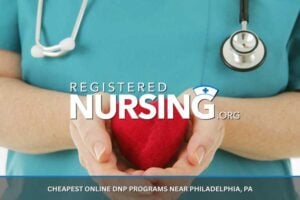 A close up of a nurse's hands holding a red heart with a stethoscope in the background.