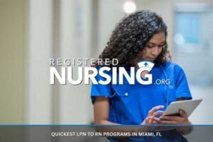 A registered nurse consults a chart on a tablet while standing in a medical building.